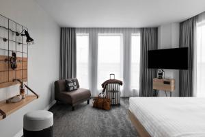 a hotel room with a bed and a chair and a television at Moxy Lyon Airport in Saint-Exupéry