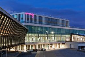 un gran edificio con coches estacionados en un estacionamiento en Moxy Lyon Airport en Saint-Exupéry