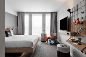 a hotel room with a bed and a tv at Moxy Lyon Airport in Saint-Exupéry