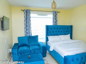 a blue bed and a chair in a room at Comfy Getaway STUDIO apartment near JKIA & SGR with KING BED, WIFI, NETFLIX and SECURE PARKING in Syokimau