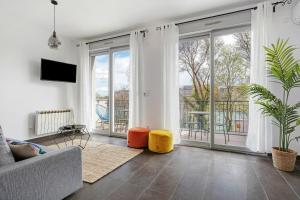 sala de estar con sofá y ventana grande en Lyon Cite-La suite Passerelle avec balcon-Caluire, en Caluire-et-Cuire