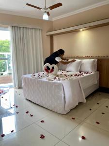 a woman is making a bed with roses on it at Hotel Lux in Poços de Caldas