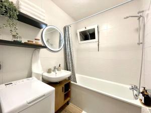 ein weißes Badezimmer mit einem Waschbecken, einer Badewanne und einem Spiegel in der Unterkunft Appartement - Lit Queen Size - Proximité Genève in Saint-Julien-en-Genevois