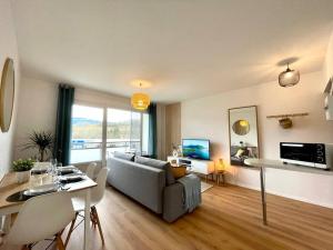 ein Wohnzimmer mit einem Sofa und einem Tisch in der Unterkunft Appartement - Lit Queen Size - Proximité Genève in Saint-Julien-en-Genevois
