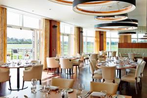 una sala da pranzo con tavoli, sedie e finestre di Lingfield Park Marriott Hotel & Country Club a Lingfield