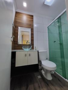 a bathroom with a toilet and a sink and a mirror at Apartamento para relaxar de frente a praia in Praia Grande