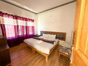 a bedroom with a large bed with red curtains at Zeejeed palace in Leh