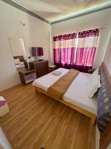 a bedroom with a large bed and a pink window at Zeejeed palace in Leh