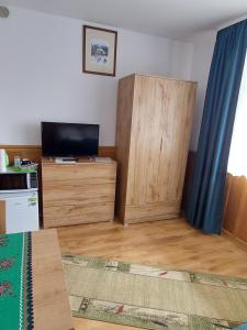 a living room with a television and a wooden cabinet at Pokoje Gościnne Zbyszko in Zakopane