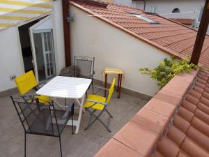 een patio met een witte tafel en gele stoelen bij "La Casita", 2 Floors Apartment, Private Parking 1 car OR 2 Bikes, Air-Cond and Terrace in Livorno