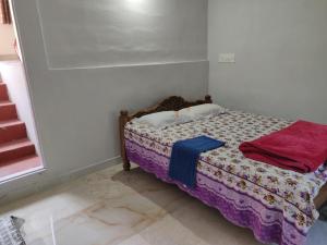 a small bedroom with a bed with purple sheets at Kaikane homestay in Madikeri