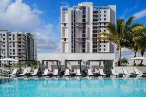 a swimming pool with chairs and a tall building at AC Hotel By Marriott Miami Brickell in Miami