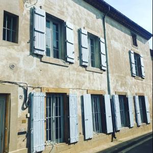 un edificio con ventanas blancas y persianas. en Les 2 Drôles d'Oiseaux, en Luc-sur-Orbieu
