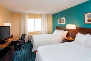 a hotel room with two beds and a flat screen tv at Fairfield Inn & Suites Greeley in Greeley