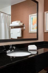 a bathroom with a sink and a mirror and towels at Fairfield Inn & Suites Greeley in Greeley