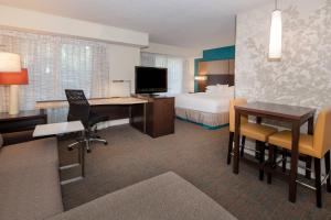 Residence Inn by Marriott Jacksonville Butler Boulevard في جاكسونفيل: غرفة في الفندق مع سرير ومكتب مع مكتب