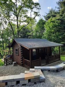 Cette cabane en rondins dispose d'une terrasse couverte et d'un toit. dans l'établissement Tiny Cabin located on the outskirts of Mohican State Park, 