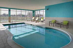 uma grande piscina com cadeiras e mesas num edifício em SpringHill Suites by Marriott Oklahoma City Midwest City Del City em Del City