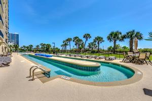 uma piscina num resort com mesas e cadeiras em South Wind Penthouse 1 em Myrtle Beach