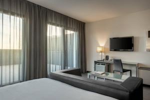 マドリードにあるAC ホテル アトーチャ ア マリオット ライフスタイル ホテルのベッド、デスク、テレビが備わるホテルルームです。