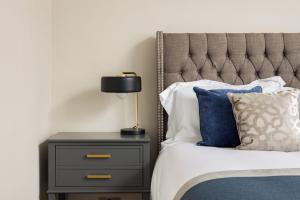 a bedroom with a bed and a nightstand with a lamp at Avari Apartments - Hatton Collection in London