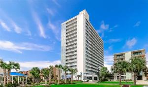 a tall white building with palm trees in front of it at Forest Dunes Penthouse 1801 in Myrtle Beach