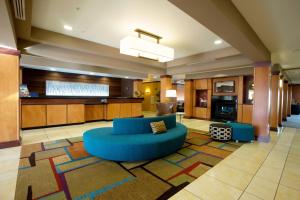 a large living room with a blue couch and a kitchen at Fairfield Inn and Suites by Marriott Muskogee in Muskogee