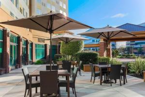 un patio con mesas, sillas y sombrillas en Courtyard by Marriott San Jose Campbell, en Campbell