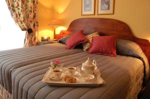 uma cama com uma bandeja com conjuntos de chá em Elonda B&B em Pretoria