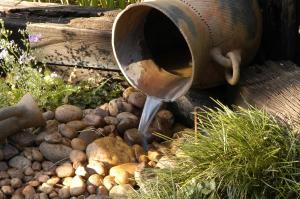 um pote de água derramando água num jardim de rochas em Elonda B&B em Pretoria