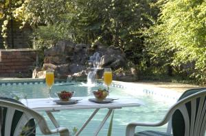 a table with two glasses of orange juice next to a pool at Elonda B&B in Pretoria