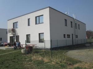 乌赫尔布罗德Polyfunkční dům Pasát的一座白色的建筑,有两个人坐在外面