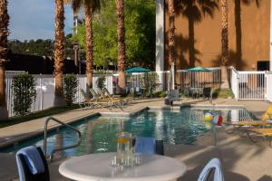 a swimming pool with palm trees and a table and chairs at Fairfield Inn Las Vegas Convention Center in Las Vegas