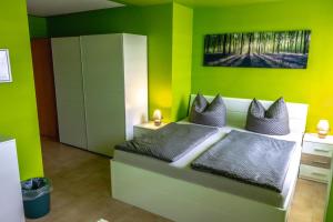 - une chambre avec des murs verts et un lit avec des oreillers dans l'établissement Pension Village, à Naumbourg