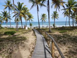 einen Holzweg zum Strand mit Palmen in der Unterkunft Paraíso na Reserva Imbassaí in Mata de Sao Joao