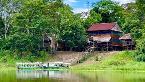 una casa a orillas de un río con un barco en Yaku Amazon Lodge & Expeditions, en Paraíso