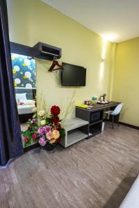 una habitación de hotel con TV y flores en una habitación en Indra Hotel Ipoh, en Ipoh