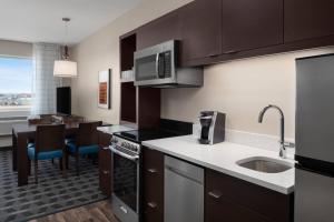 a kitchen with brown cabinets and a dining room at TownePlace Suites by Marriott Twin Falls in Twin Falls