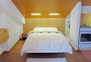 ein großes weißes Bett in einem Zimmer mit Küche in der Unterkunft Ferienwohnung in Anzère, an der Skipiste in Anzère