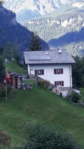 une maison blanche sur une colline avec des montagnes en arrière-plan dans l'établissement Alpe Monte Massella, à Poschiavo