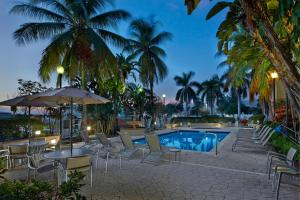 uma piscina de resort com cadeiras, mesas e palmeiras em Fairfield Inn & Suites Boca Raton em Boca Raton