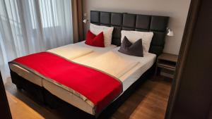 a bedroom with a large bed with red pillows at Gideon Hotel in Nürnberg