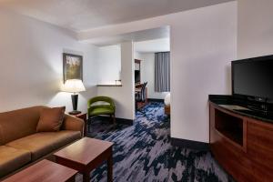 a hotel room with a couch and a flat screen tv at Fairfield Inn & Suites Detroit Livonia in Livonia