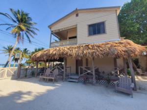 a building with a straw roof on the beach at The Bounty in Caye Caulker