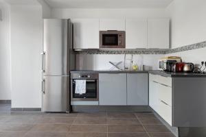 a kitchen with white cabinets and a stainless steel refrigerator at Lyon Cité- Appartement vue Rhône terrasse-Caluire in Caluire-et-Cuire