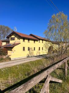 ein gelbes Haus mit einem Zaun davor in der Unterkunft Hotel e B&B Il Mulino in Vaiano