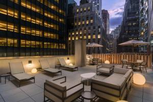 eine Dachterrasse mit Stühlen, Tischen und Gebäuden in der Unterkunft Courtyard New York Downtown Manhattan/Financial District in New York