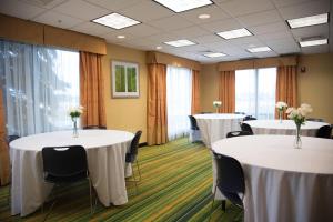una sala de conferencias con 2 mesas y sillas con flores. en Fairfield Inn & Suites by Marriott Muskegon Norton Shores, en Norton Shores