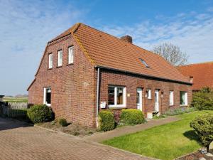 a brick house with a red roof on a street at Traumhafter Nordseeurlaub im modernen Ferienhaus mit großem Garten, Kamin und Strandkorb in Werdum