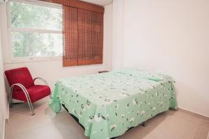 1 dormitorio con 1 cama y 1 silla roja en Leblon Aconchegante, en Río de Janeiro